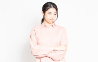 腕を組み、思いつめた表情で視線を落とす女性。父親が憎い気持ちを抱えている