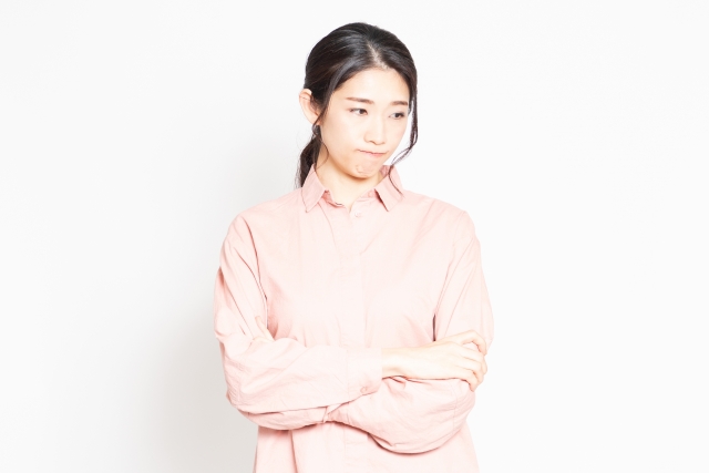 腕を組み、思いつめた表情で視線を落とす女性。父親が憎い気持ちを抱えている